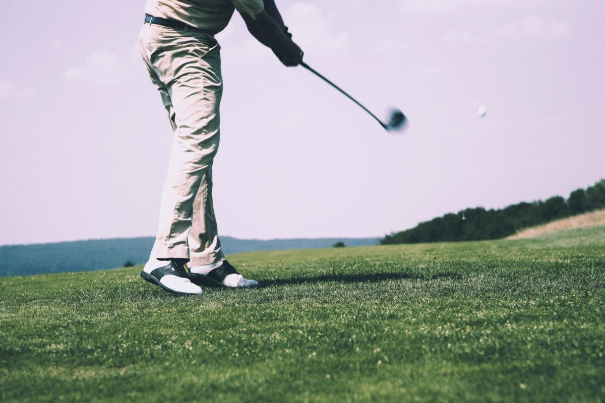 man hitting golf ball on golf course to highlight article on improving golf handicap